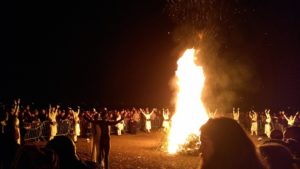 Bonfire at the Beltane Fire Festival 2019, Calton Hill, Edinburgh. The reunited May Queen and Green Man face the fire, while dancers stop to raise their arms to heaven.